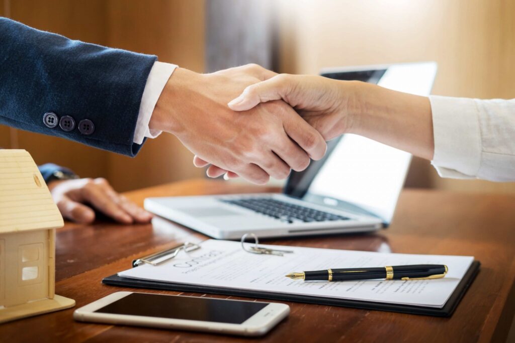 Two parties are shaking hands after signing a real estate contract.