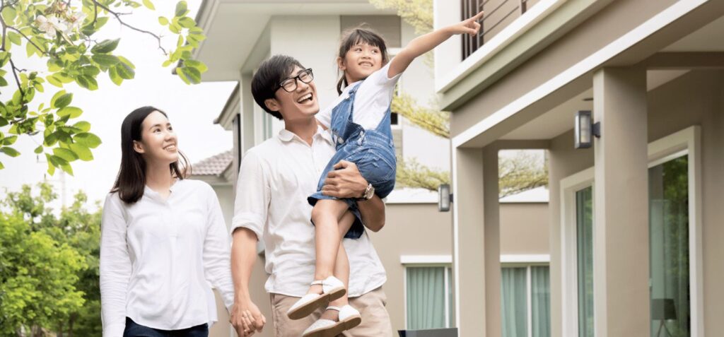 A happy couple with their child are walking towards their house.